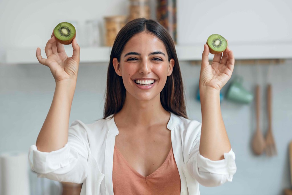 Women holding two kiwi fruit