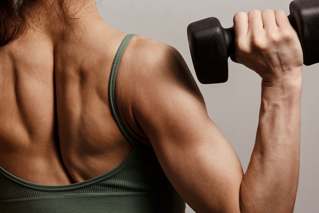 Back shot of woman holding dumbbell