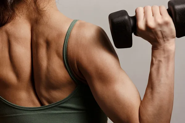 Back shot of woman holding dumbbell