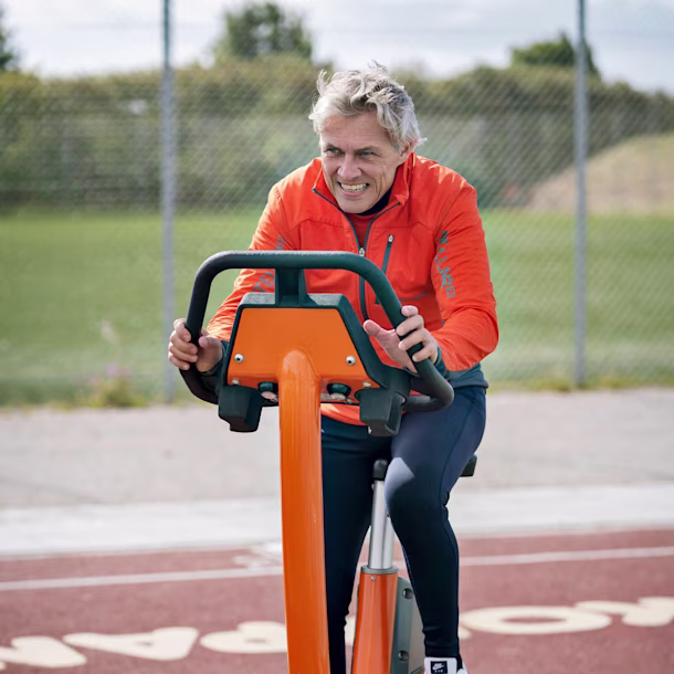 man die op een stationaire cardiofiets buiten traint