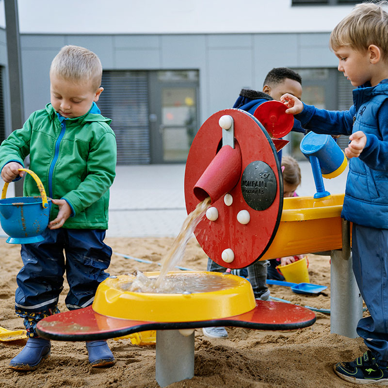 children in kindergarten playing with sand and water playground equipment