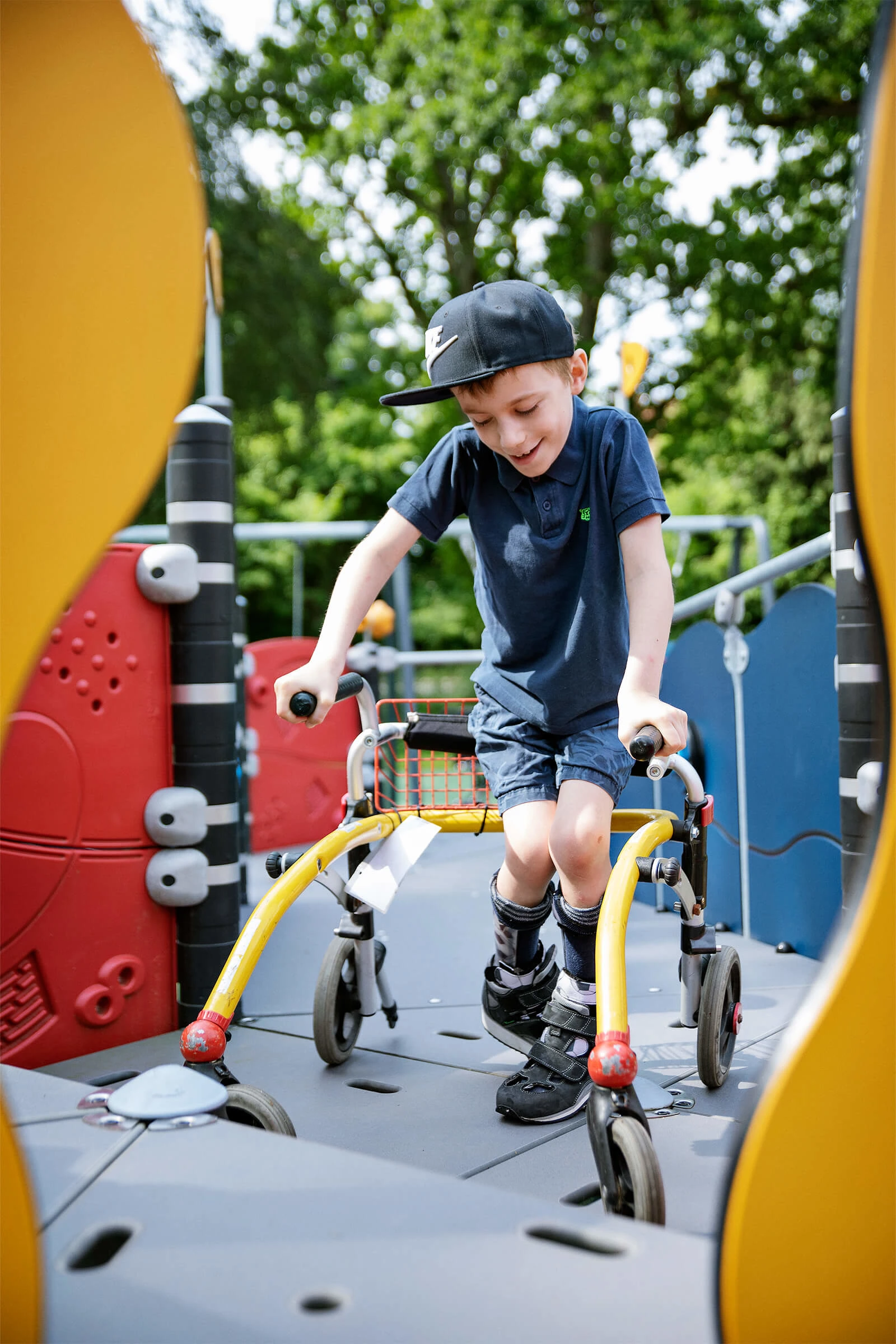 niño con andador en un parque infantil altamente inclusivo con rampa para jugar a la torre