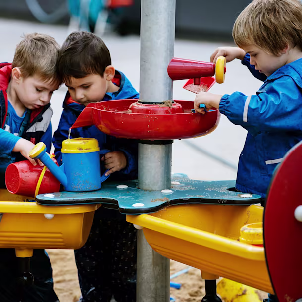 Preschool children using sand and water tables for sensory play. When playground planning, you should consider creating zones for different age groups. Sensory play is great for younger children and those with additional needs.