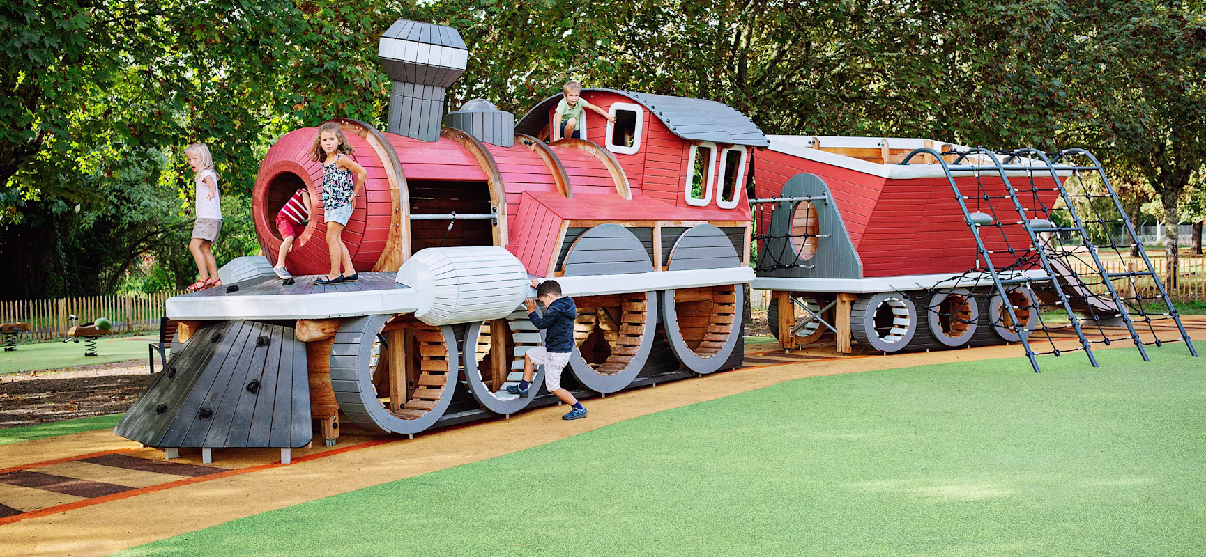 Children playing on custom wooden playground train in Saint-Médard