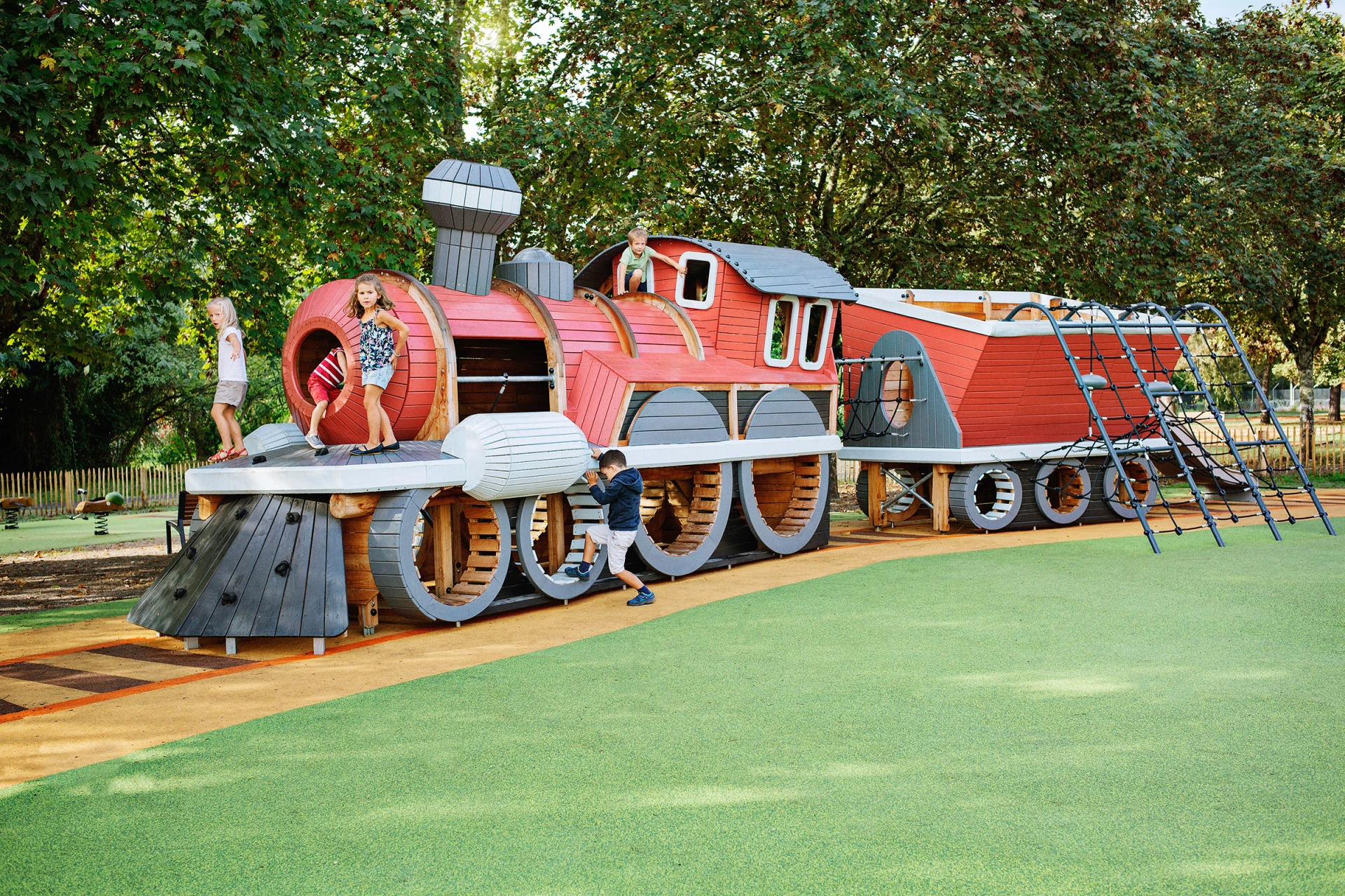 Children playing on custom wooden playground train in Saint-Médard