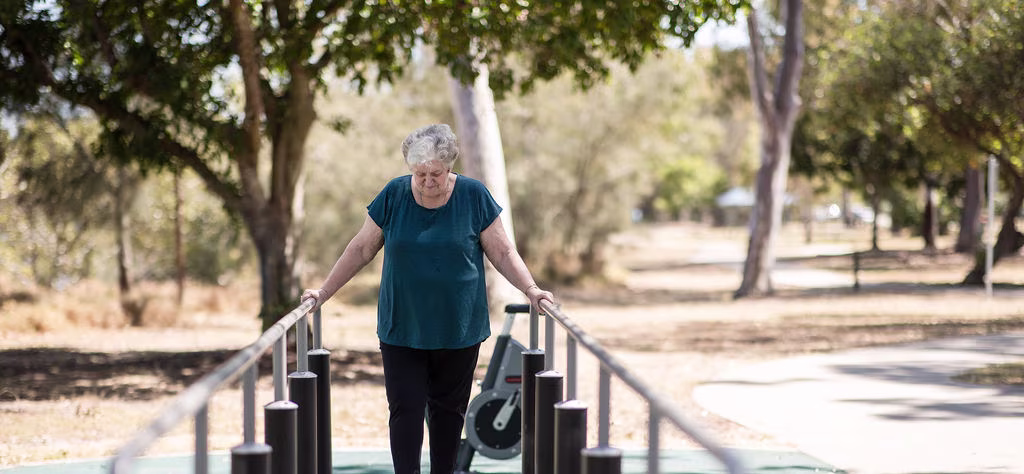 two seniors working out on outdoor fitness equipment in a park