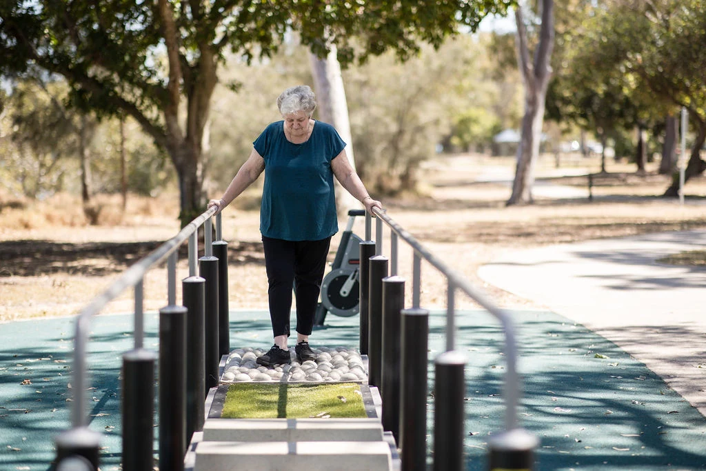 two seniors working out on outdoor fitness equipment in a park