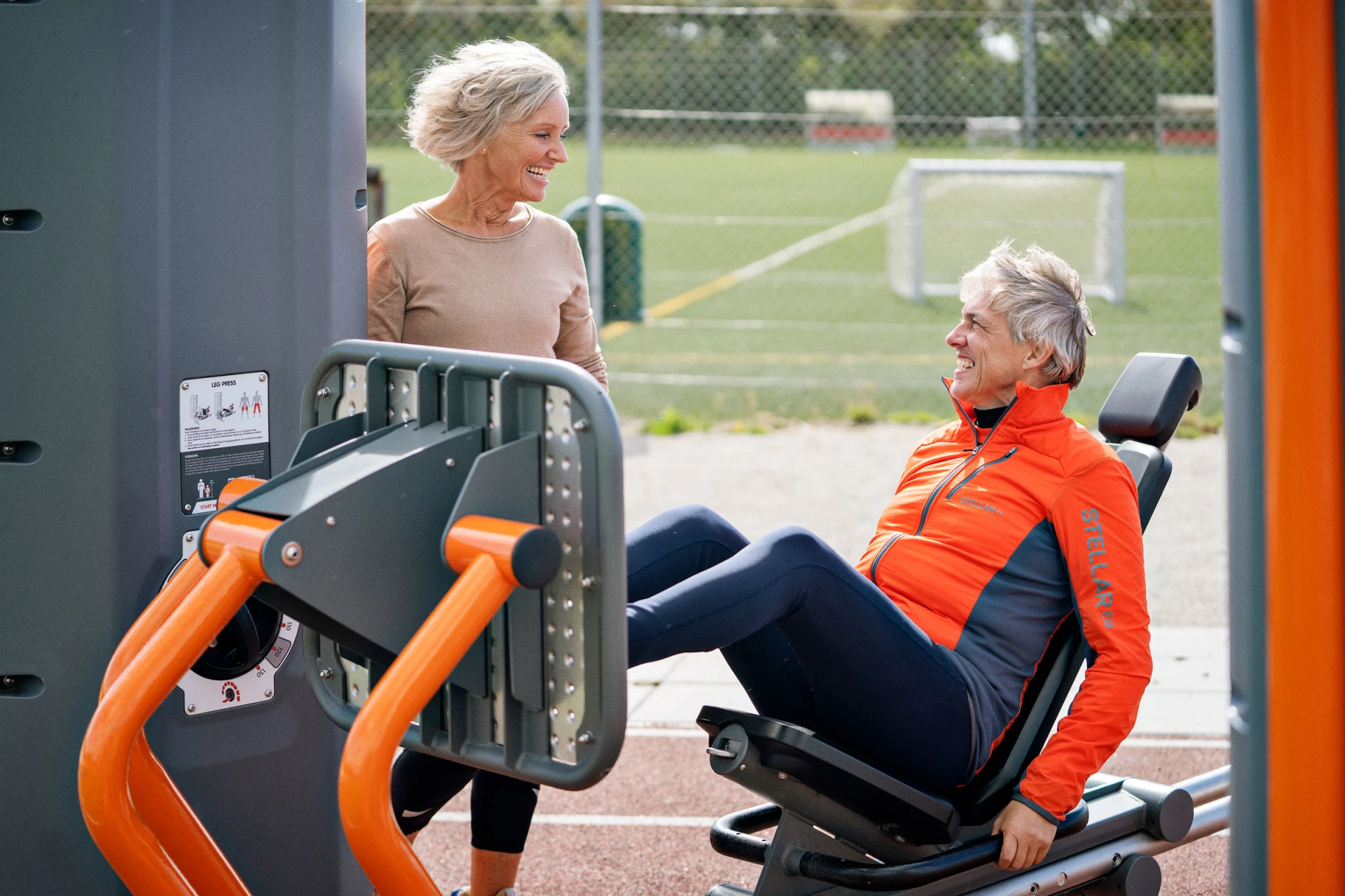 Deux personnes âgées s'entraînant sur un appareil de musculation de fitness en plein air, dans un parc.