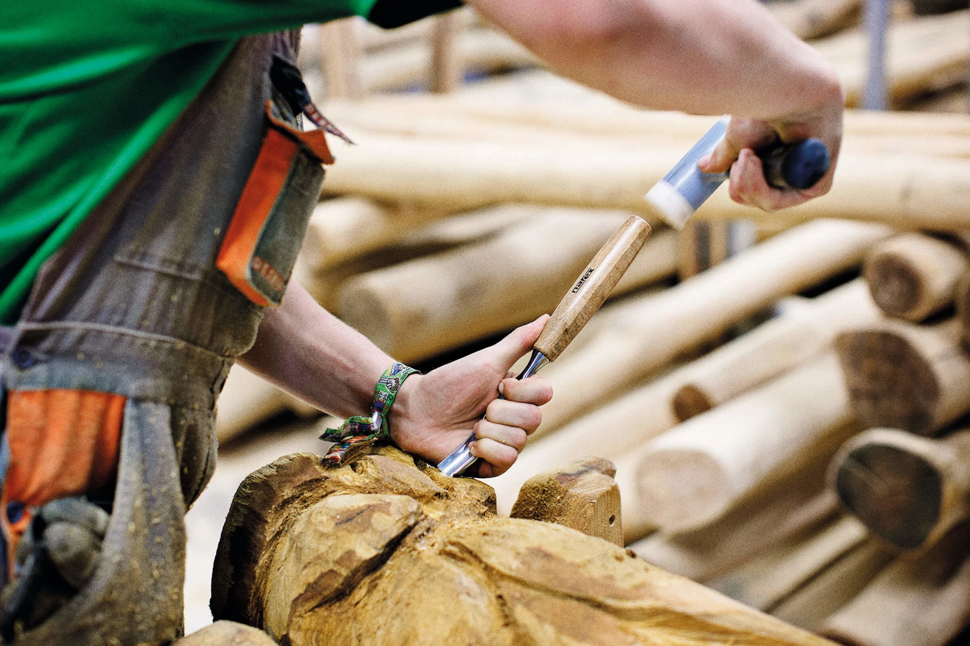 A man using a tool on a log of robinia wood at the KOMPAN factory in Brno. If you're looking for a natural aesthetic as part of your playground equipment plan, robinia wood is a great choice.