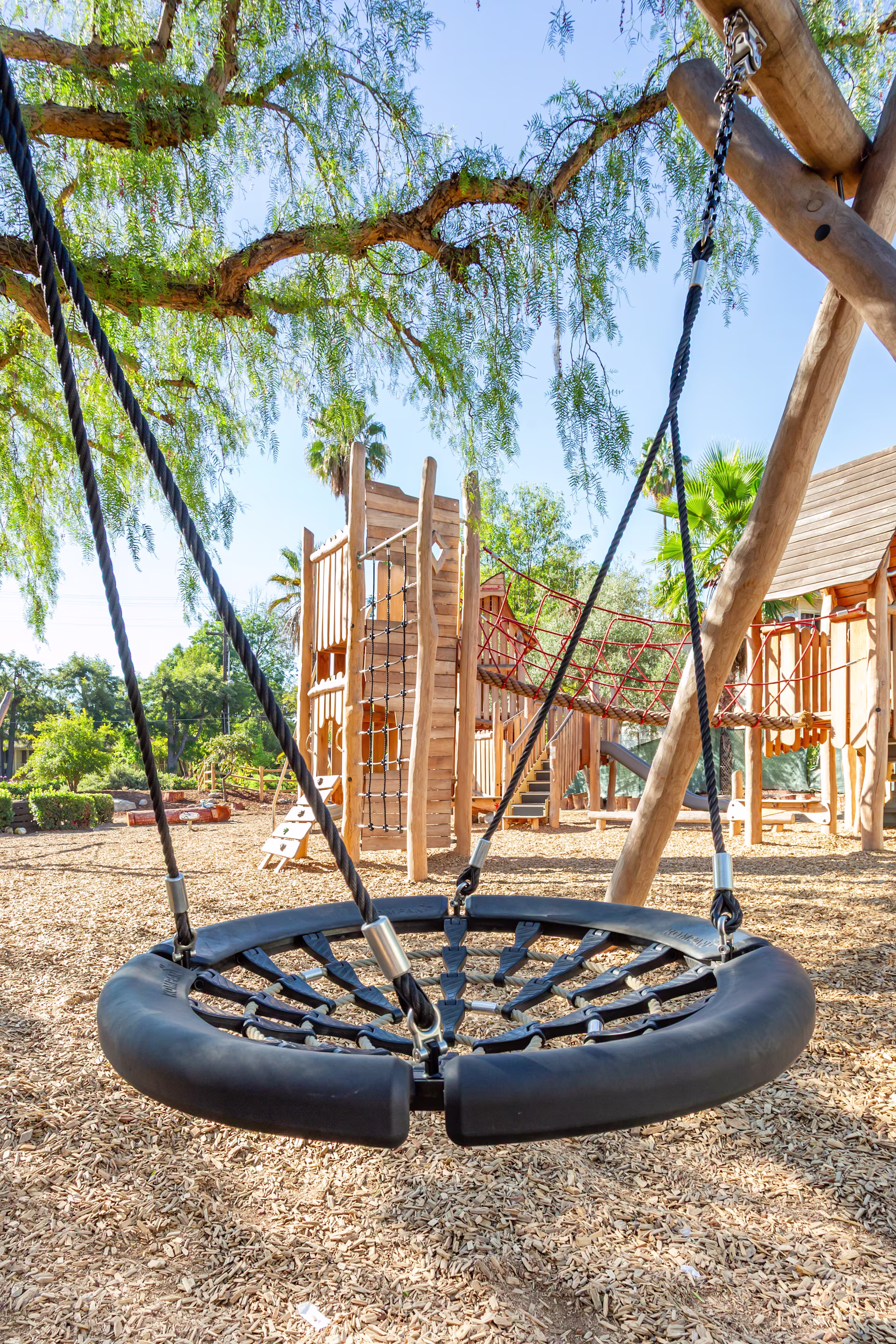 Close-up shot of a basket swing with a clear sightline showing a wooden climbing tower in the background at Sequoyah School in Pasadena, California