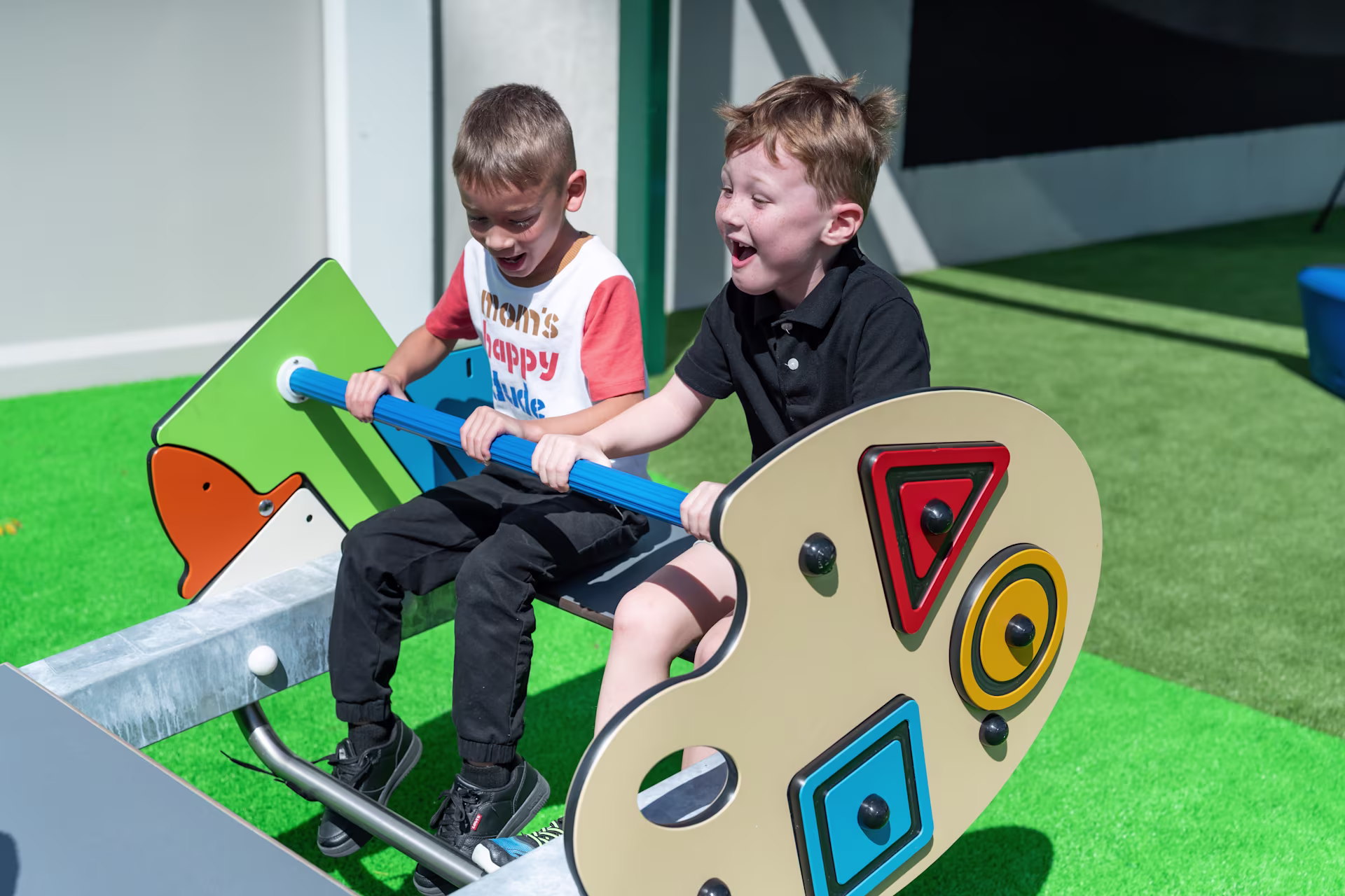 Two elementary-aged students playing on school playground equipment, featuring custom play panels, from KOMPAN