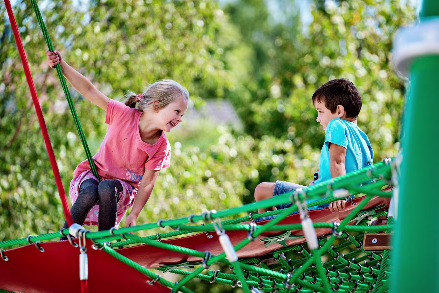 Dos escolares jugando en un parque infantil de KOMPAN.