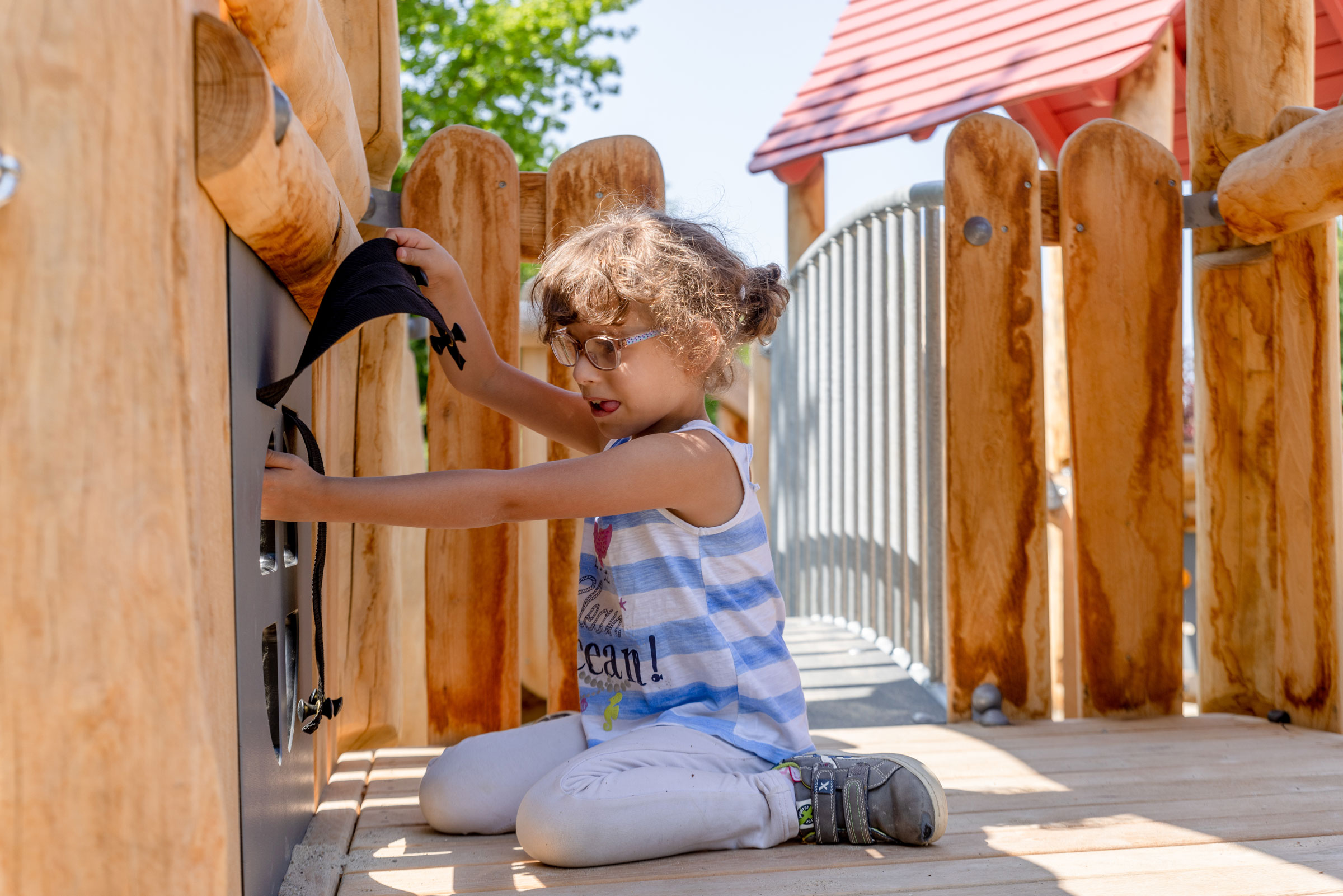 Mädchen eines heilpädagogischen Kindergartens in Deutschland, das an einem Spielwand-Element spielt
