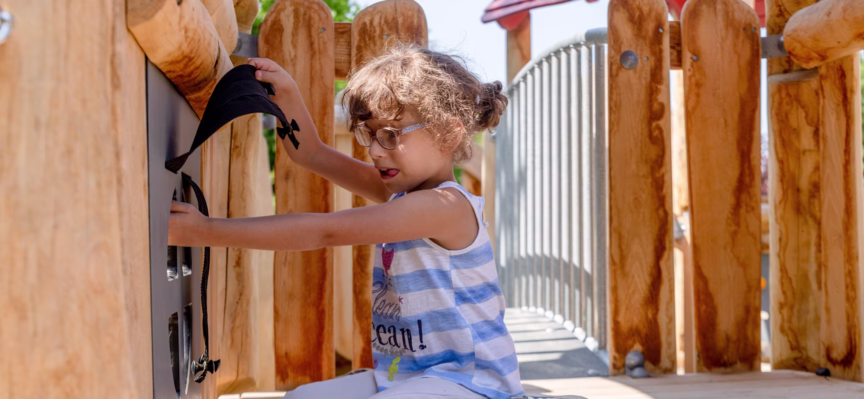 Mädchen eines heilpädagogischen Kindergartens in Deutschland, das an einem Spielwand-Element spielt