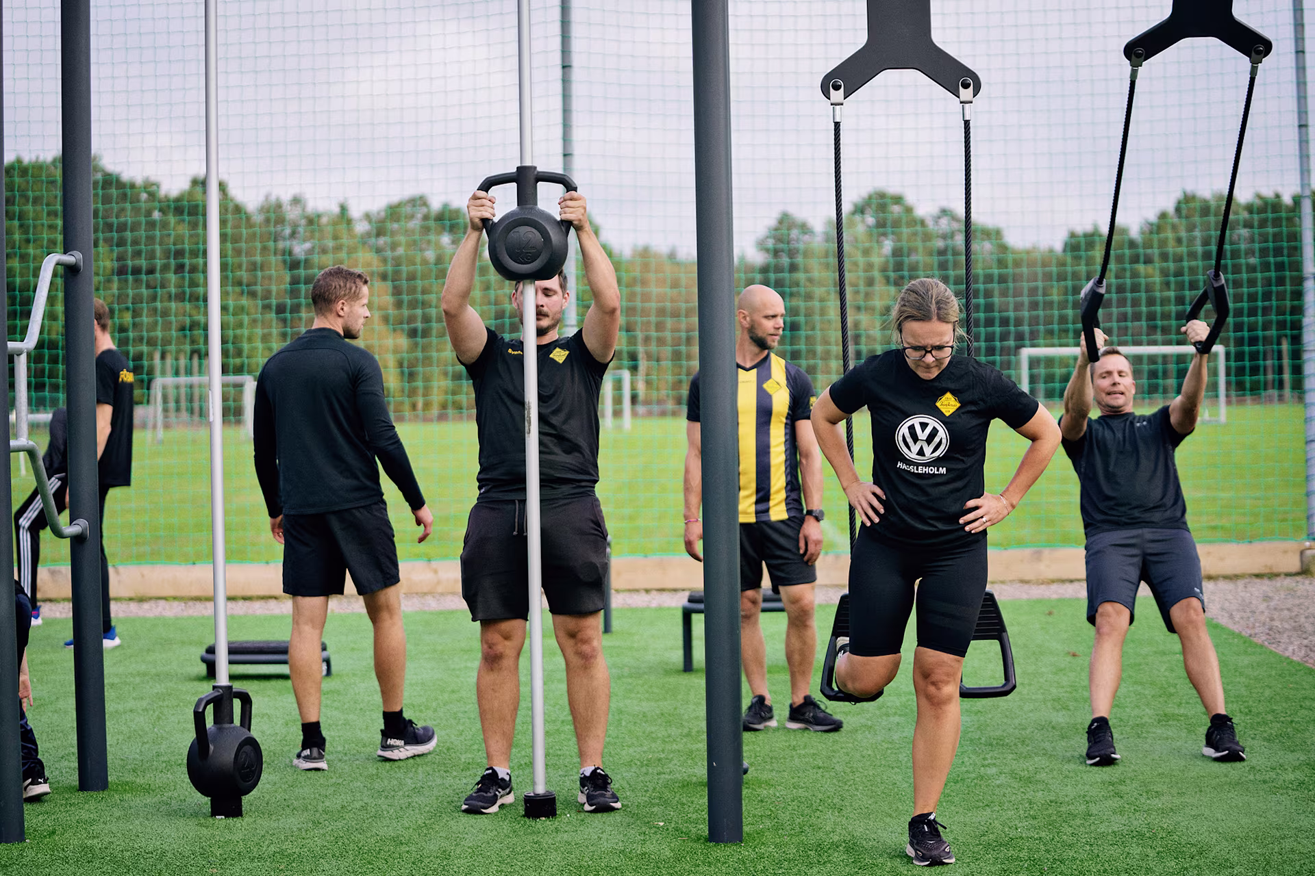 Personer som tränar i ett utegym vid en fotbollsplan