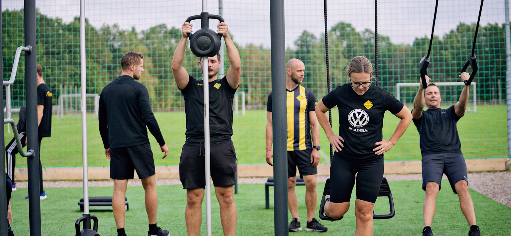 Personer som tränar i ett utegym vid en fotbollsplan