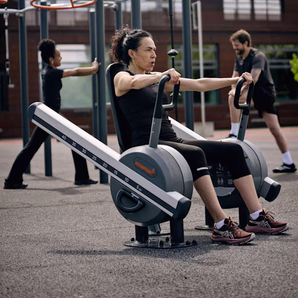 People in a park using outddor strength training machines