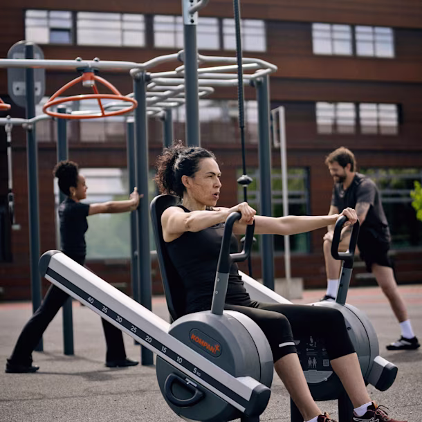 People in a park using outddor strength training machines