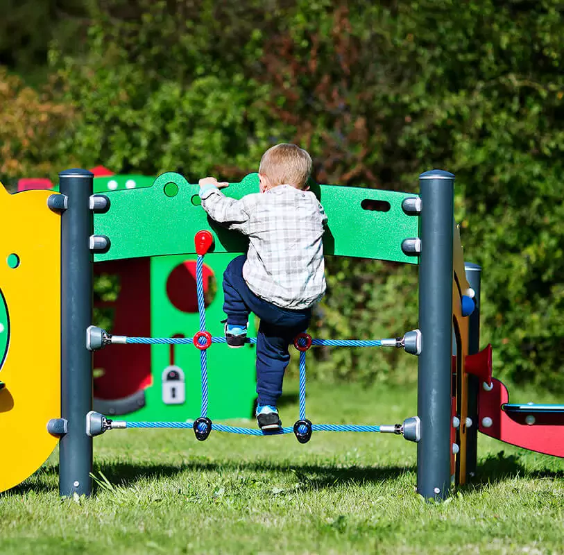 Toddler climbing on a play system designed for toddlers