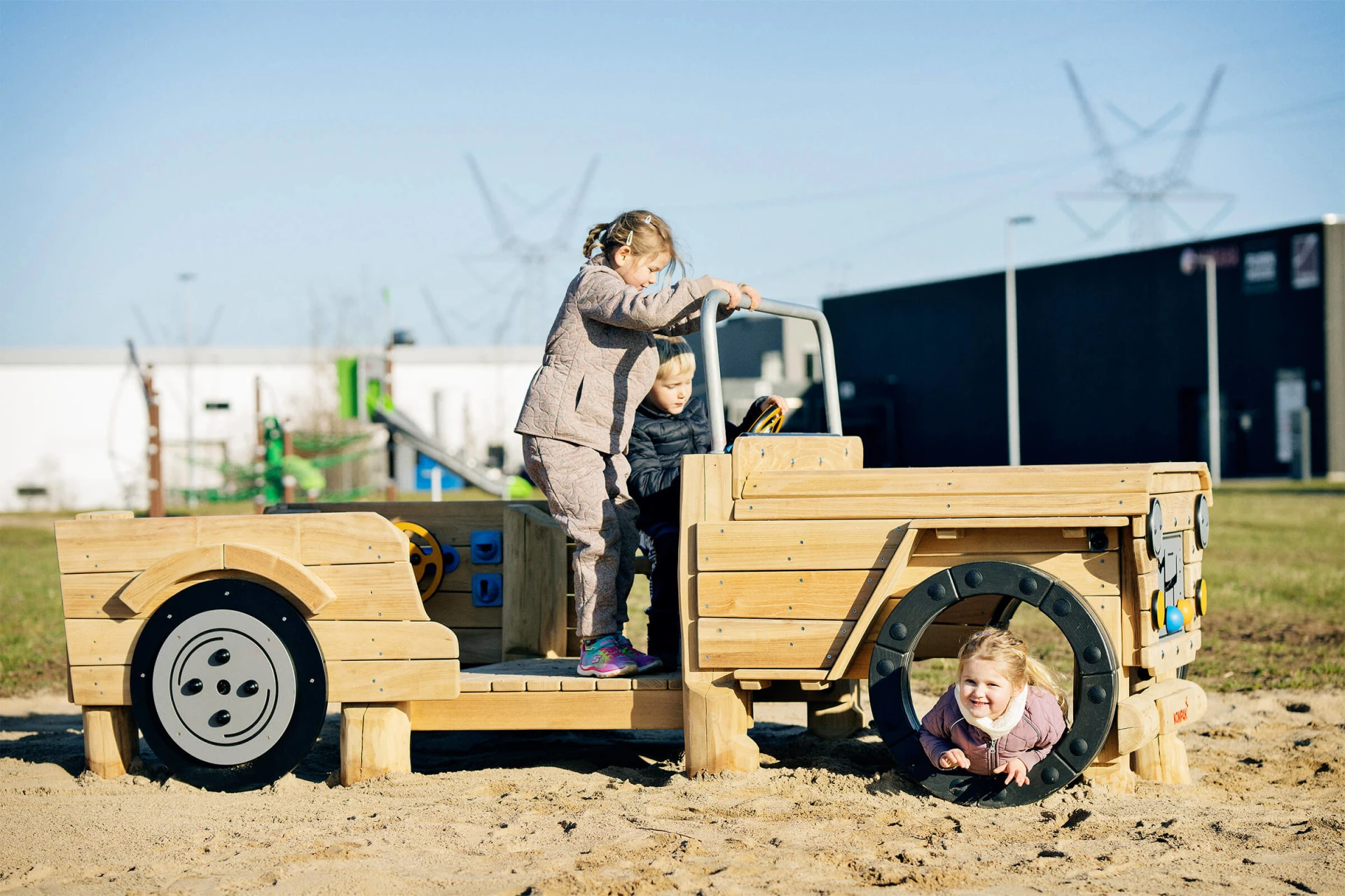 Børn leger på en legepladsbil i træ med tema 