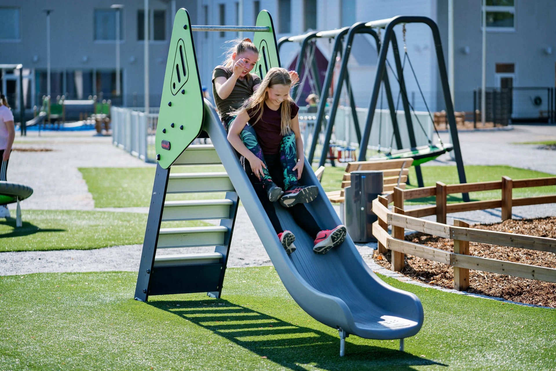 girls sliding down a playground slide on a school playground