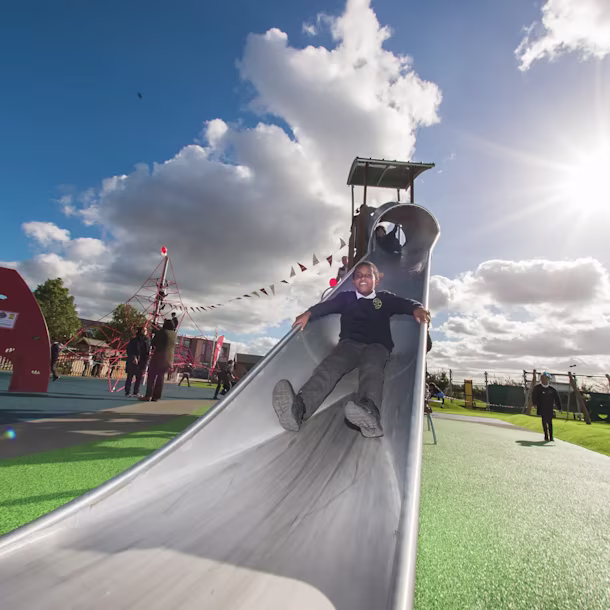 girls sliding down a playground slide on a school playground