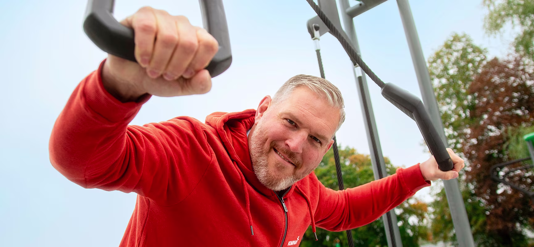 Christian Stucki steht vor einem Outdoor-Fitnessbereich seines Partners KOMPAN.