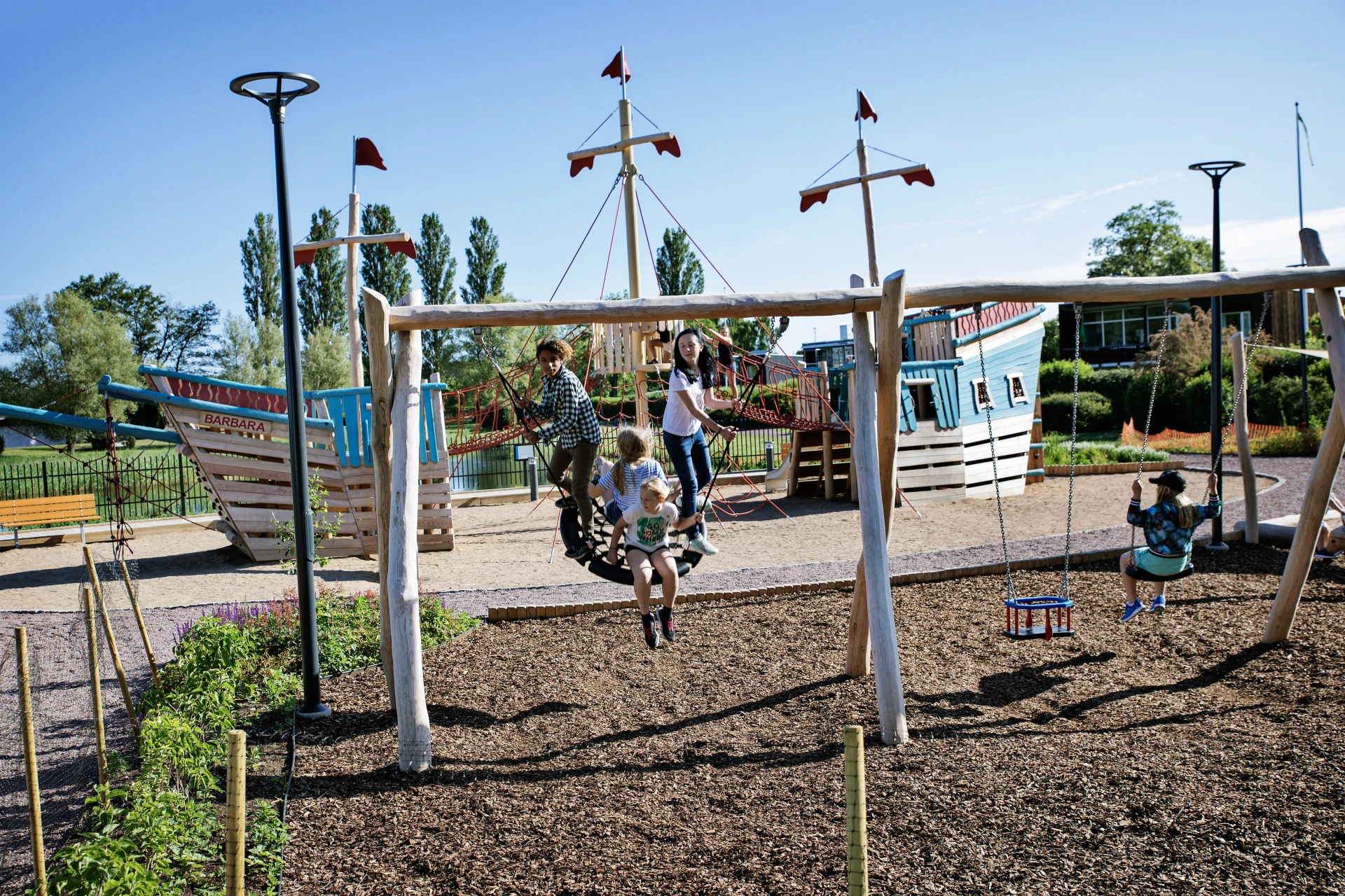 children swinging on nature wooden playground