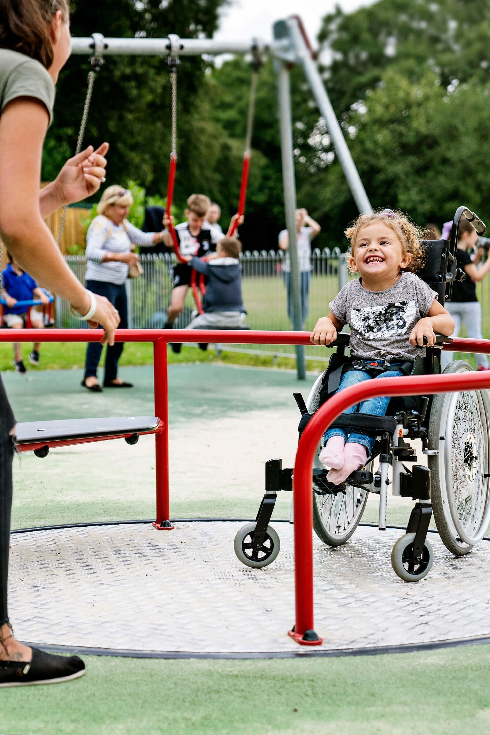 An excited young girl in a wheelchair playing on an inclusive playground