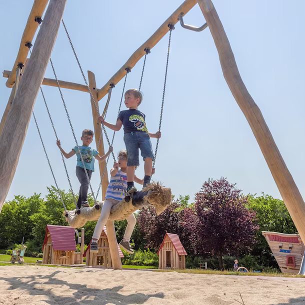 Kinder schaukeln auf einer Kokoswellen-Schaukel aus Robinienholz in Alfeld, Deutschland