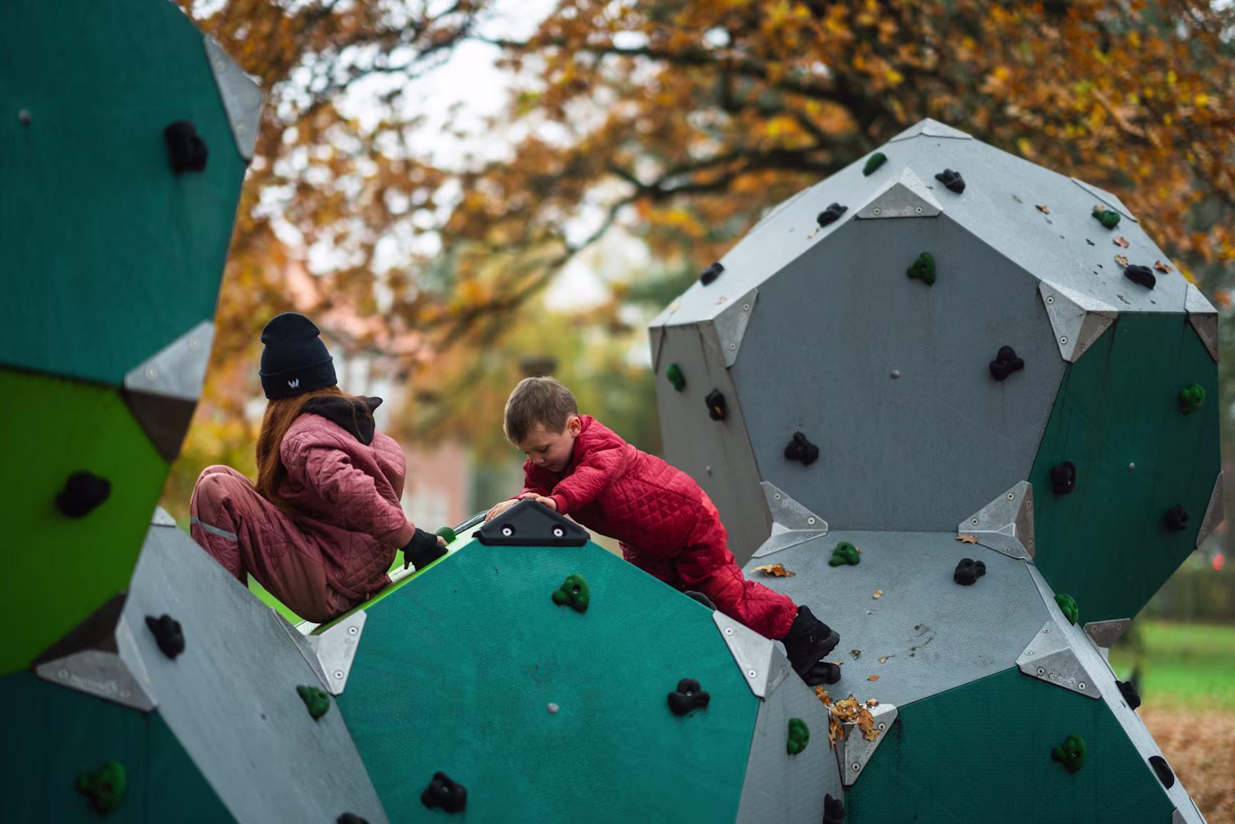 un niño y una niña trepando por los bloques de escalada del parque infantil