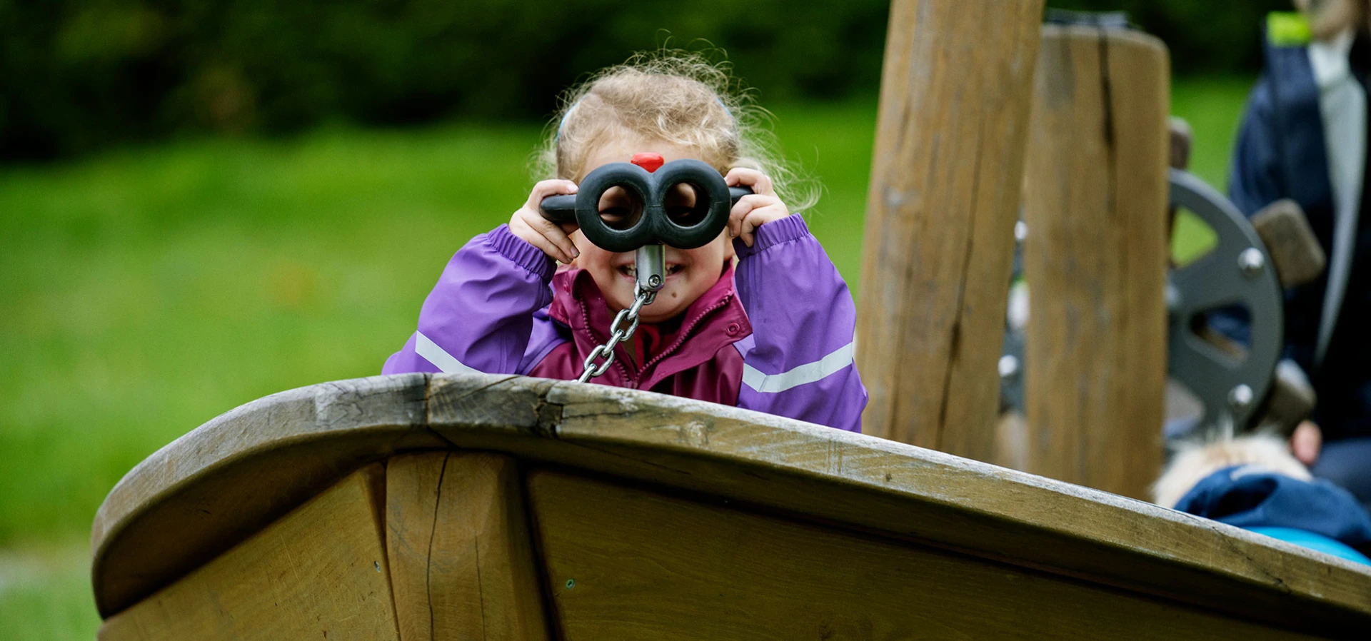 Girl looking through binoculars on a playground  
