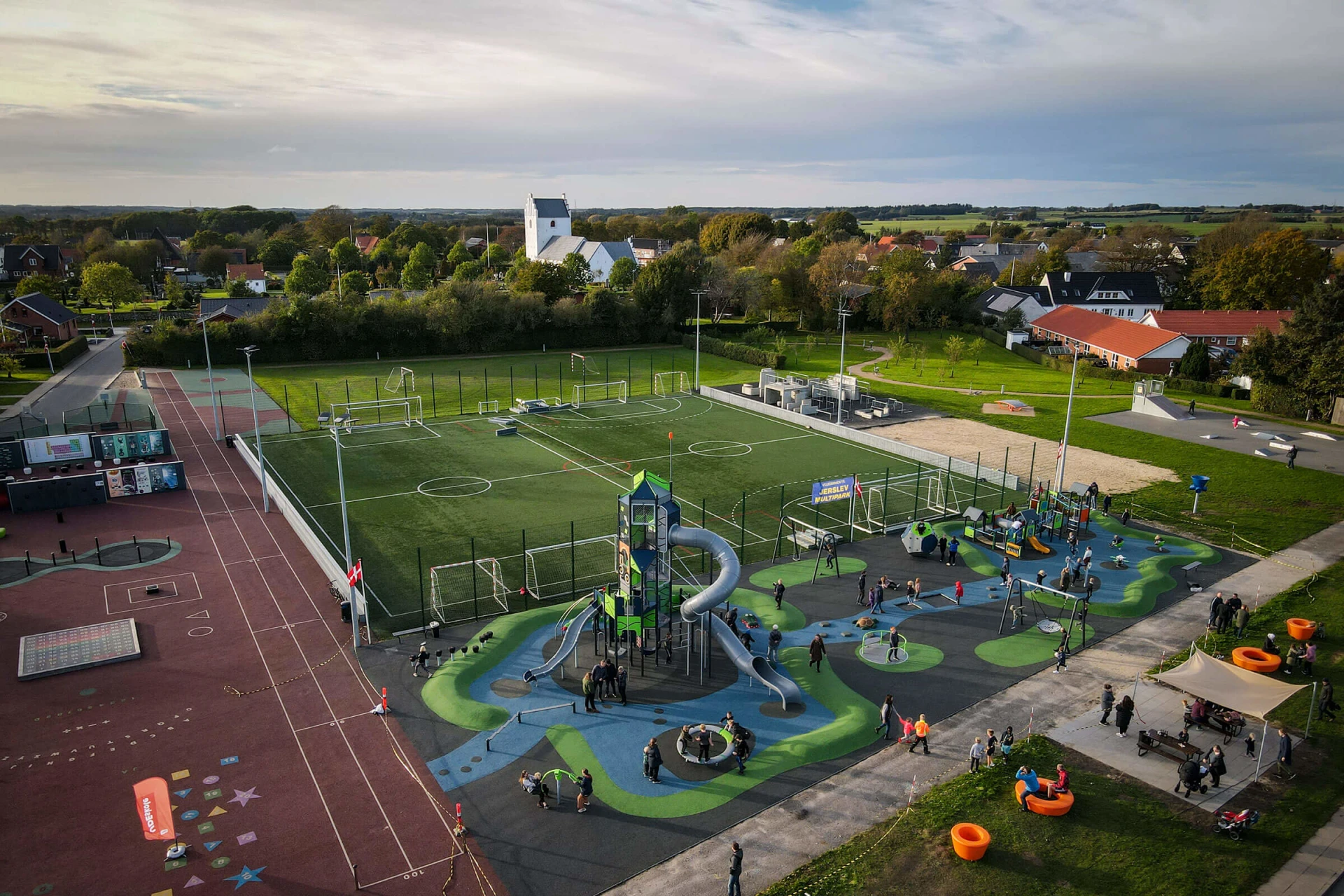 Et luftfoto af en legeplads med en fodboldbane i baggrunden.