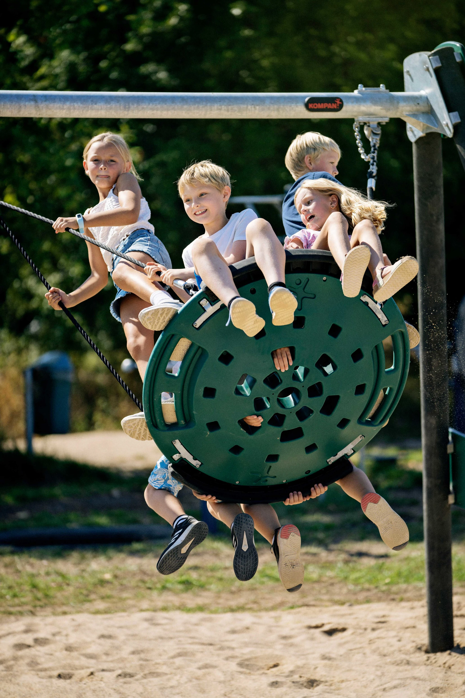 un grupo de niños se balancea en un columpio fabricado con materias primas recicladas