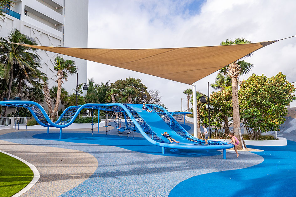 Children playing on a large blue climbing and sliding structure at DC Alexander Park in Fort Lauderdale, Florida