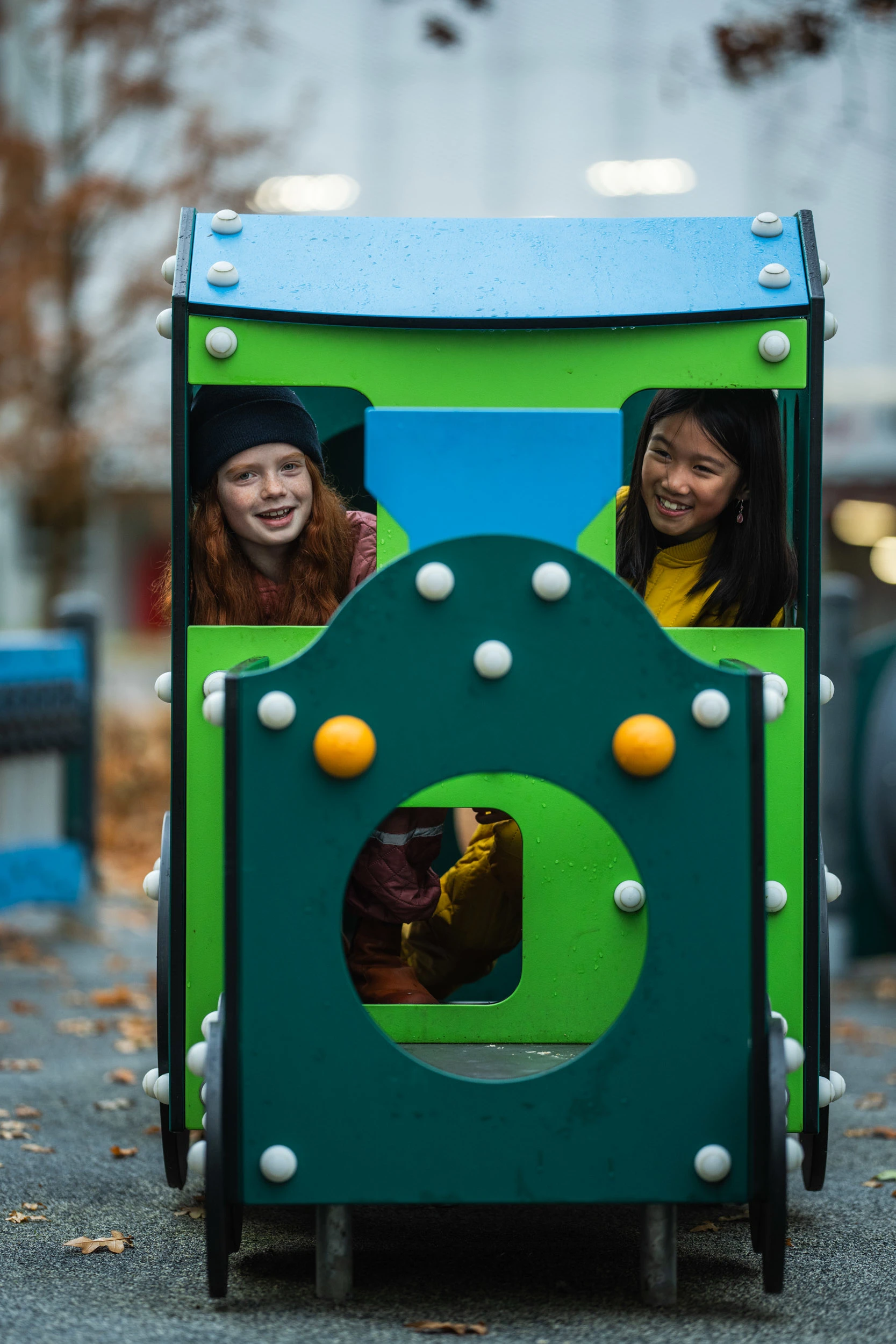 two girls playing on train themed playground equipment