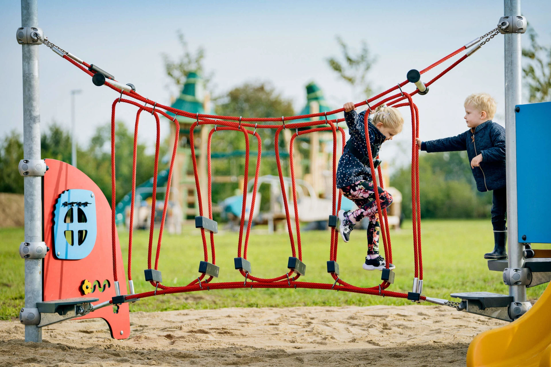 preschoolers playing on a mini playground climbing trail