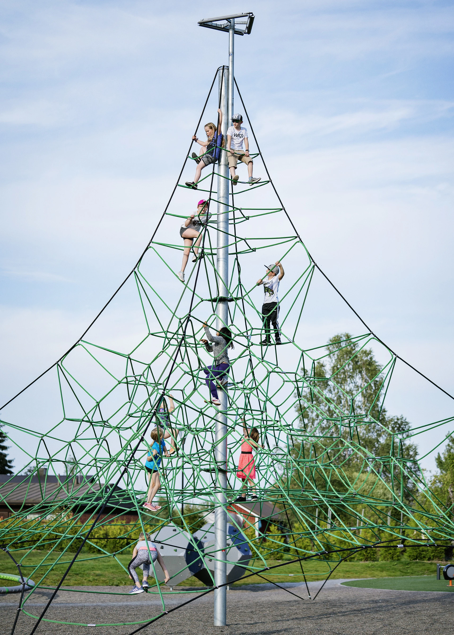 A group of children climbing a tall rope play structure