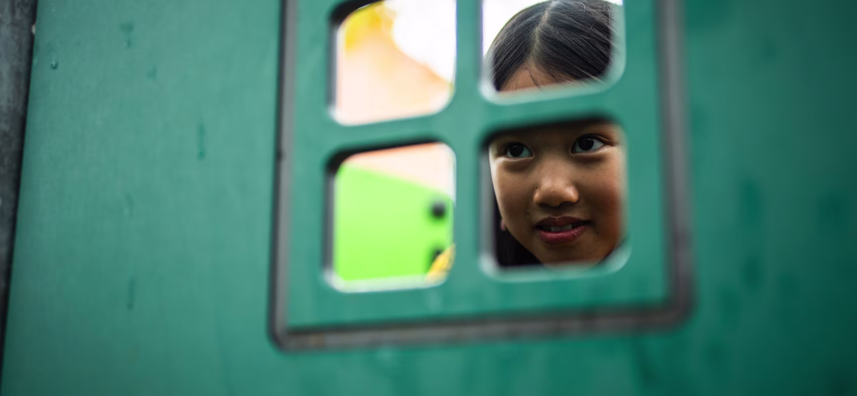 girl looking out of a window in a greener playground panel