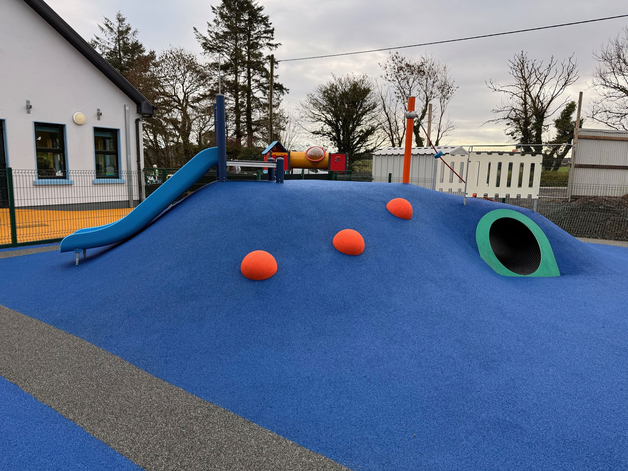 A slide and tunnel in blue safety surfacing