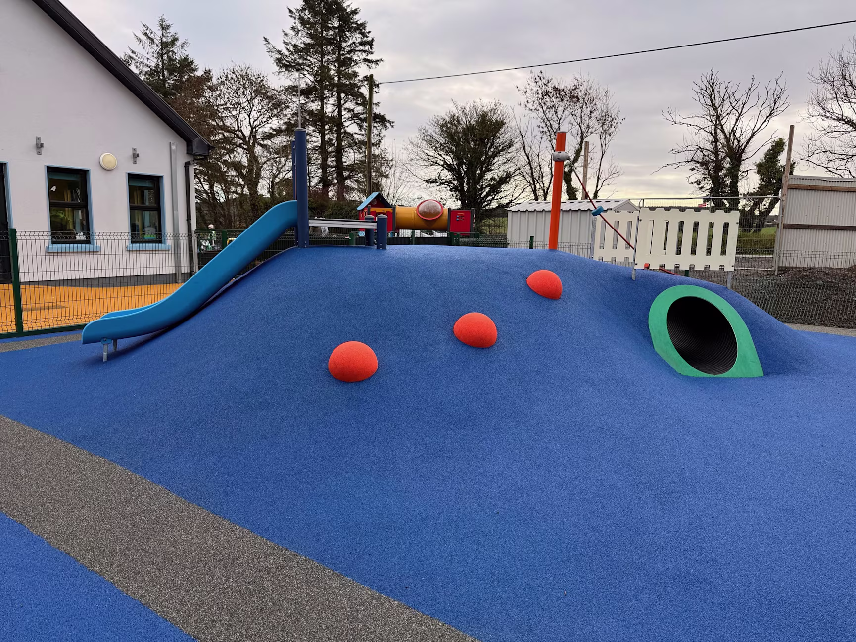 A slide and tunnel in blue safety surfacing