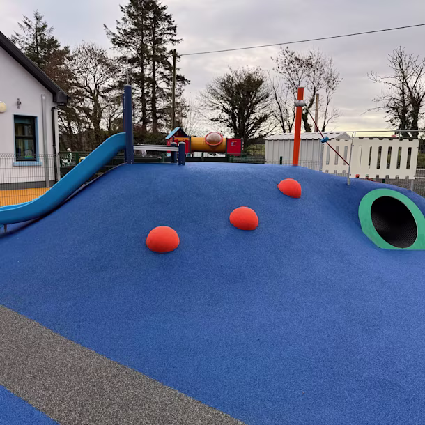 A slide and tunnel in blue safety surfacing