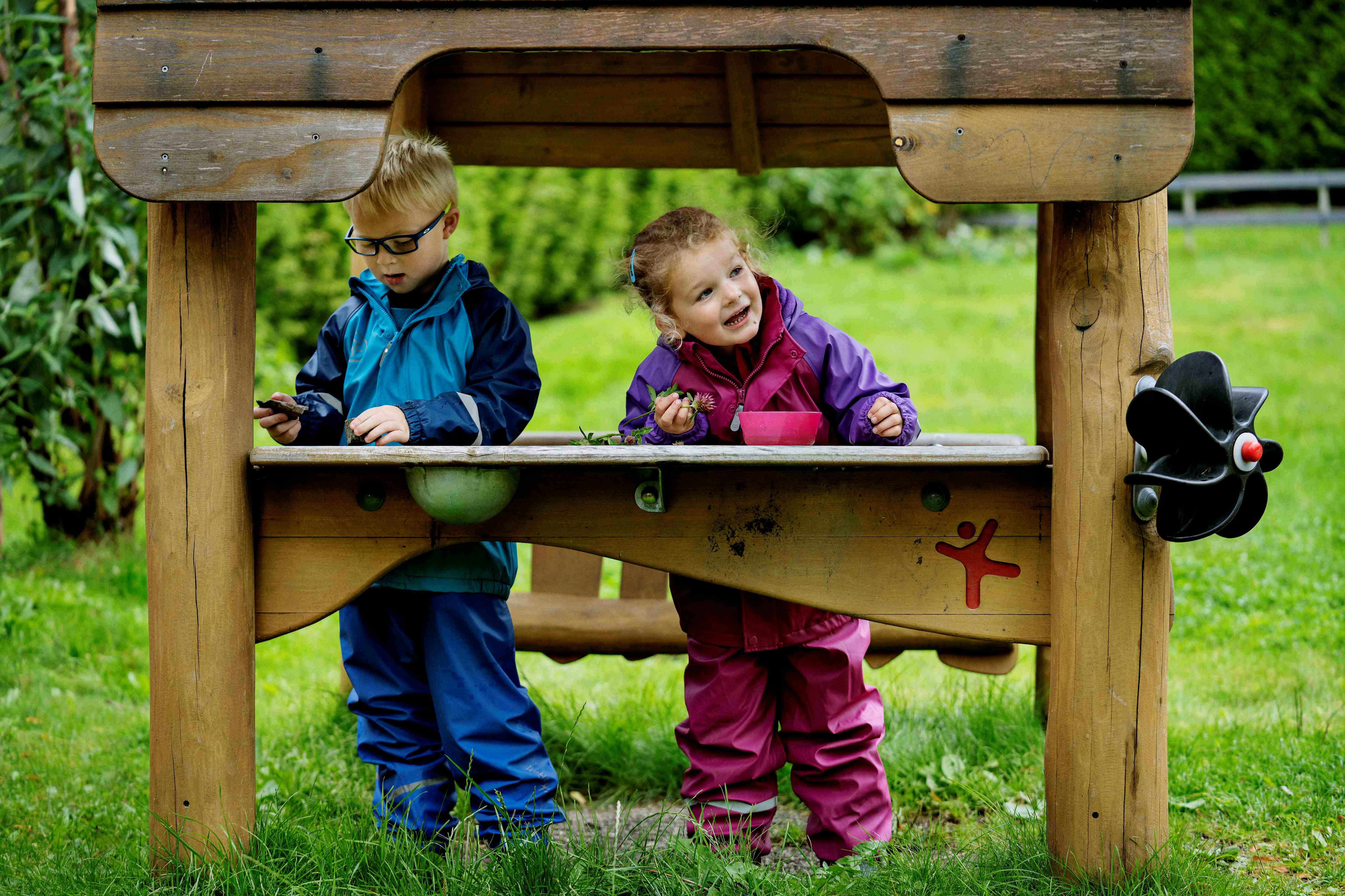 Two children playing with sand on  a wooden structure