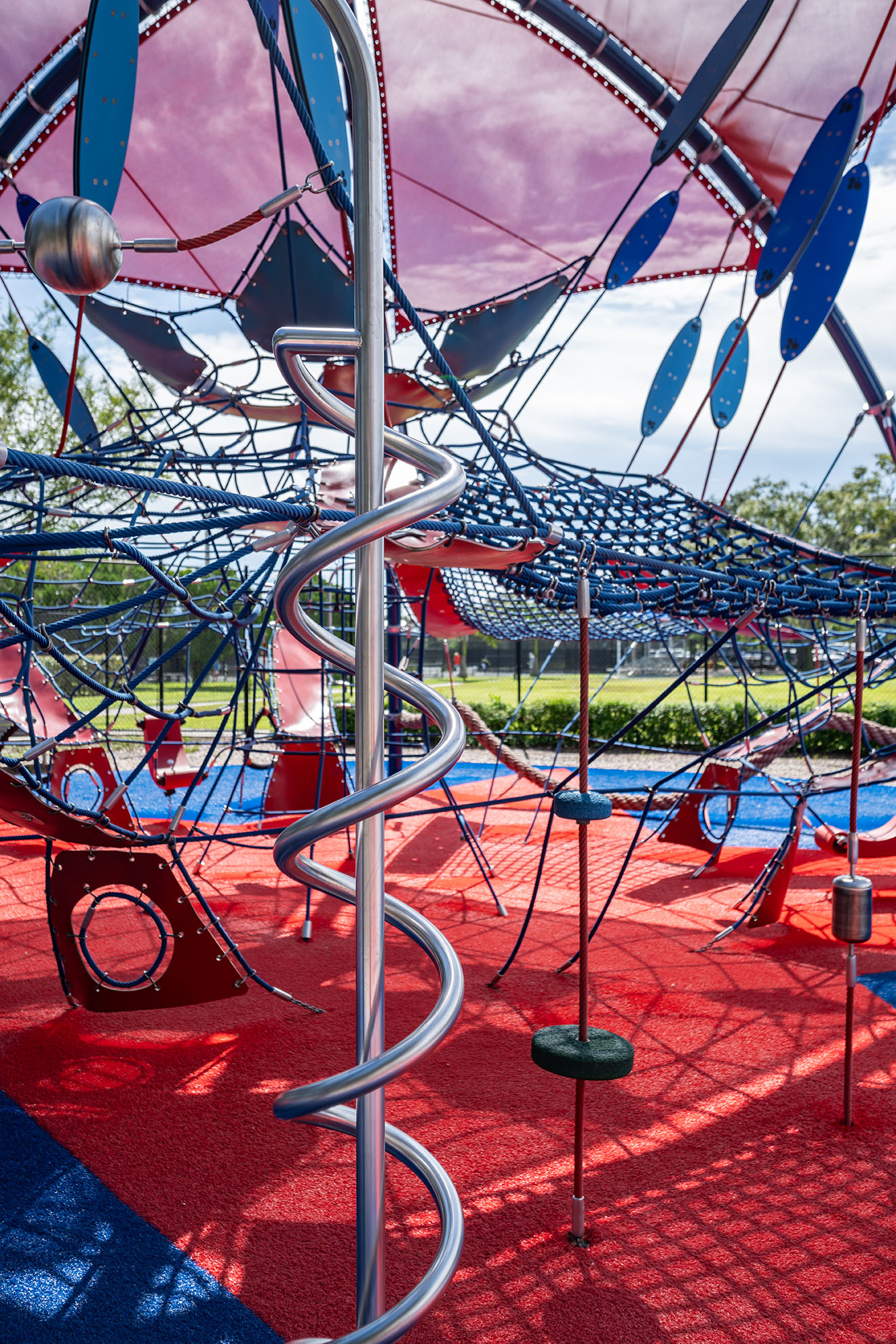Close up shot of elements inside a shaded KOMPAN climbing dome, featuring a red and blue color palette 