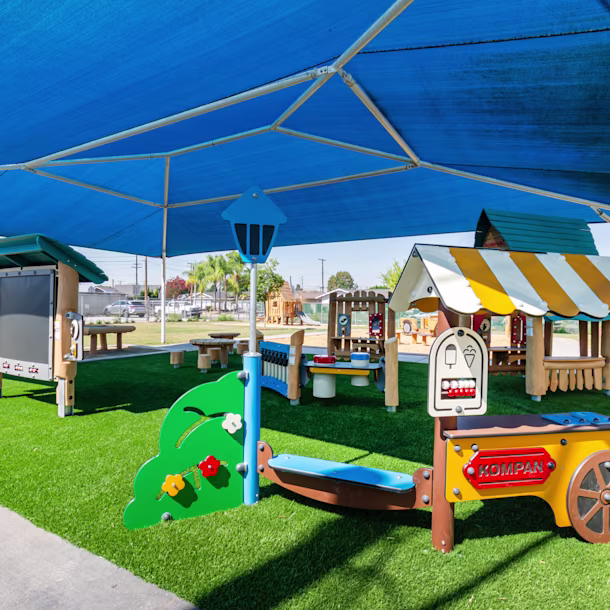 Shaded commercial playground equipment, featuring themed equipment, a blackboard, musical play panel, and more, at Maybrook Elementary in Whittier, California
