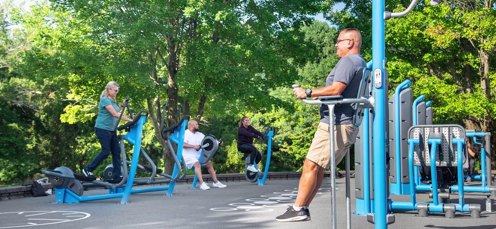adults working out on outdoor fitness equipment