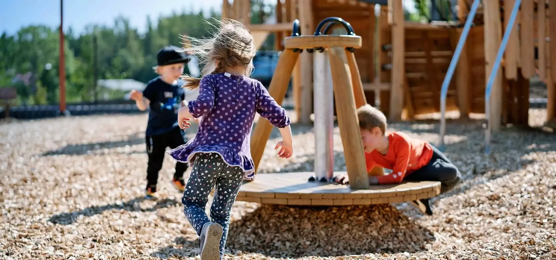 Children playing on a robinia wood playground spinner