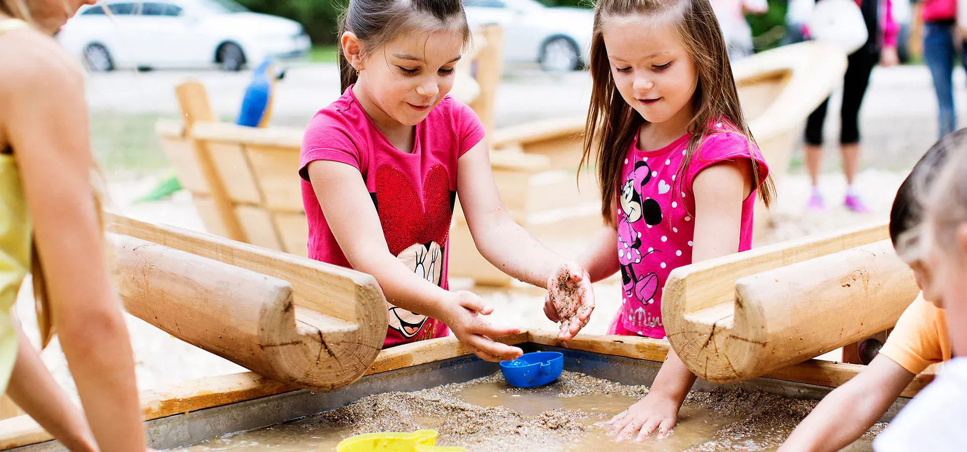 children playing on a robinia sand and water playground table hero image