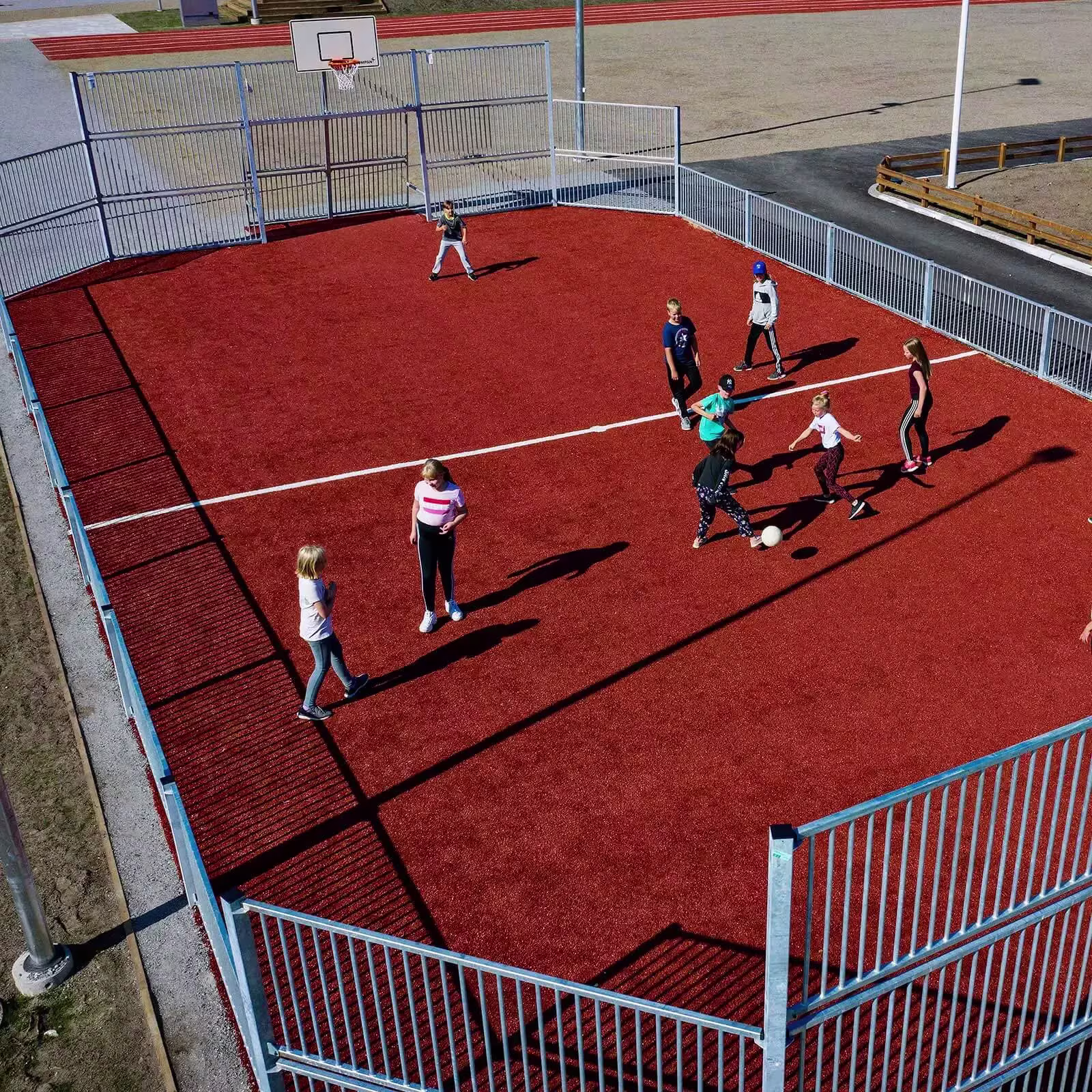 niños de secundaria jugando al fútbol en una pista polideportiva