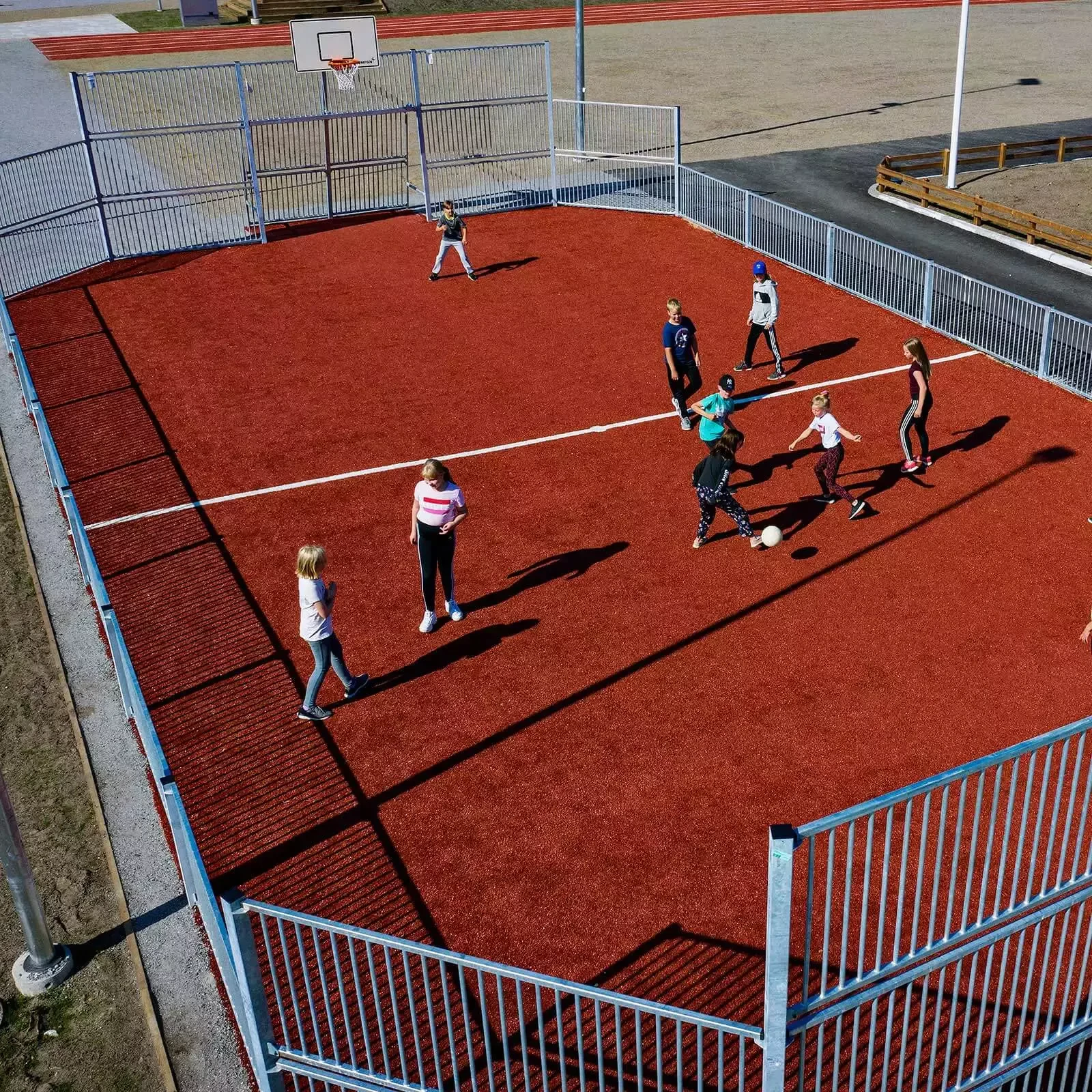 children in secondary school playing football on a multisport court